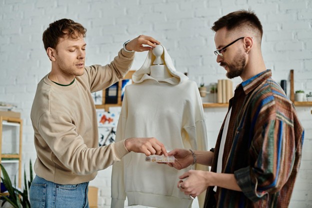 Two fashion designers collaborate on creating custom apparel, transforming a plain white hoodie into something unique.